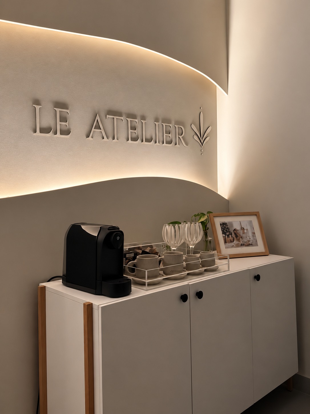 Parede assinada Le Atelier com iluminação suave e cantinho de café do atelier